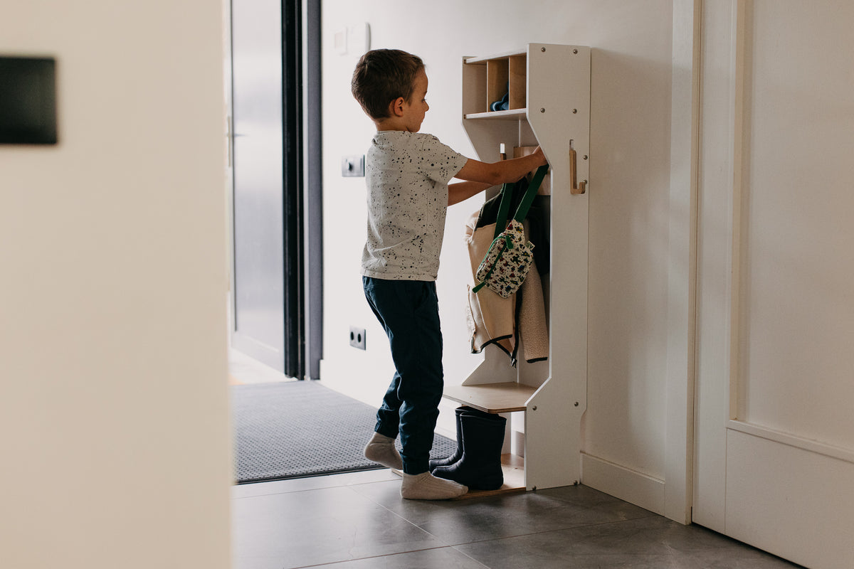 Barn nýtir fataskápinn sjálfstætt til að hengja upp jakka og tösku.