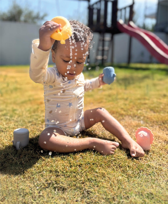 Barn úti að leika með sílíkon baðdýr og hella vatni úr gíraffa.