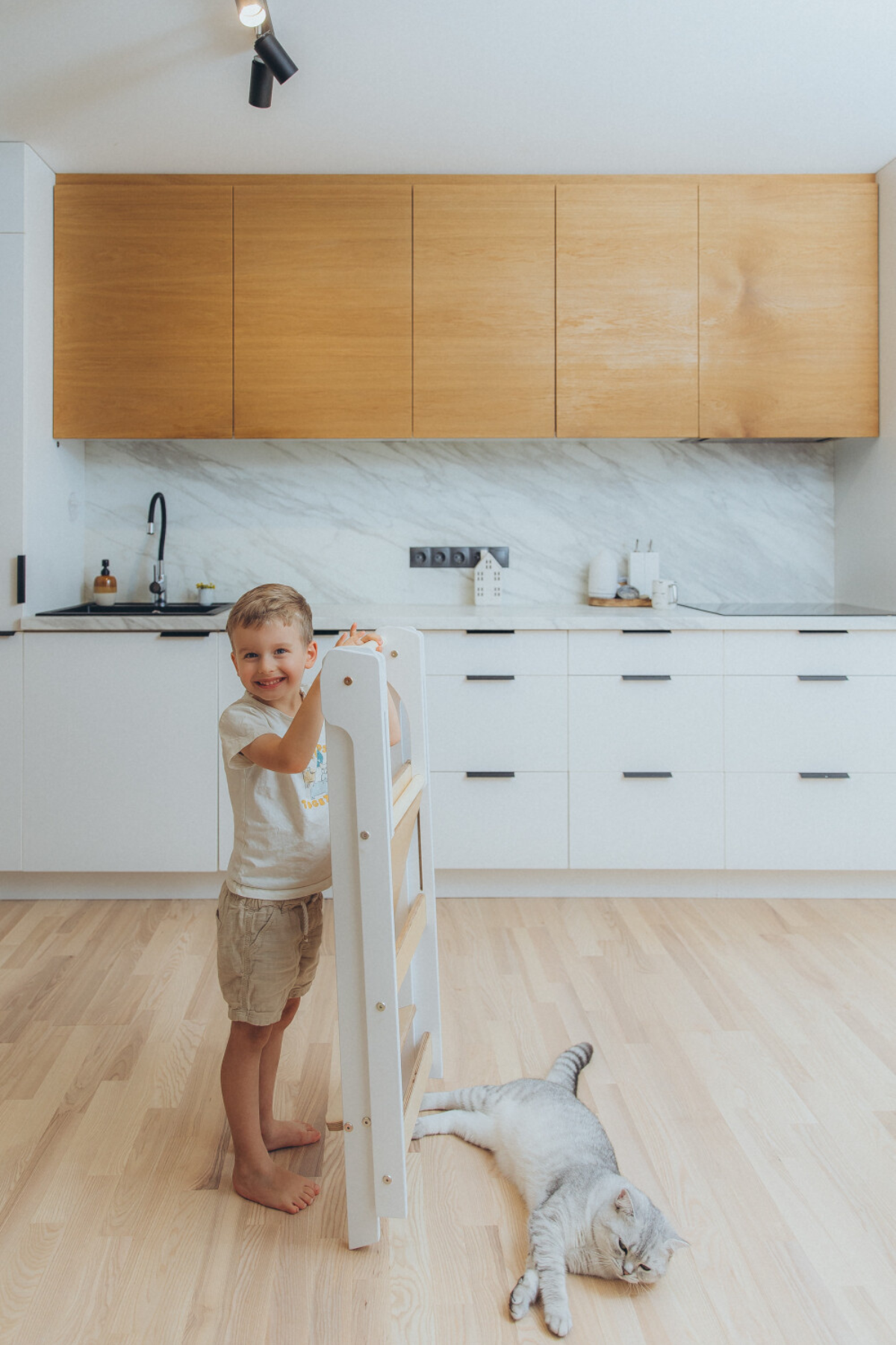 Barn heldur á samanbrjótanlegum Montessori hjálparturn, klappturn í fallegu eldhúsi.