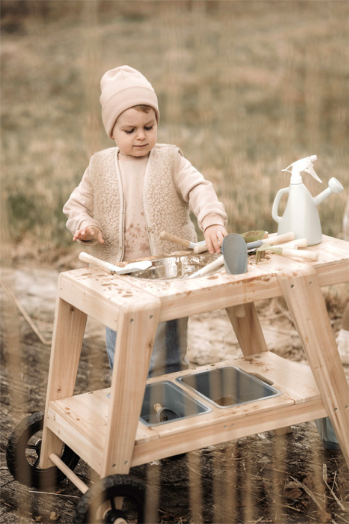 Barn að leika með Skóflusett frá Small Foot í útieldhúsi með sandi, mold og garðverkfærum