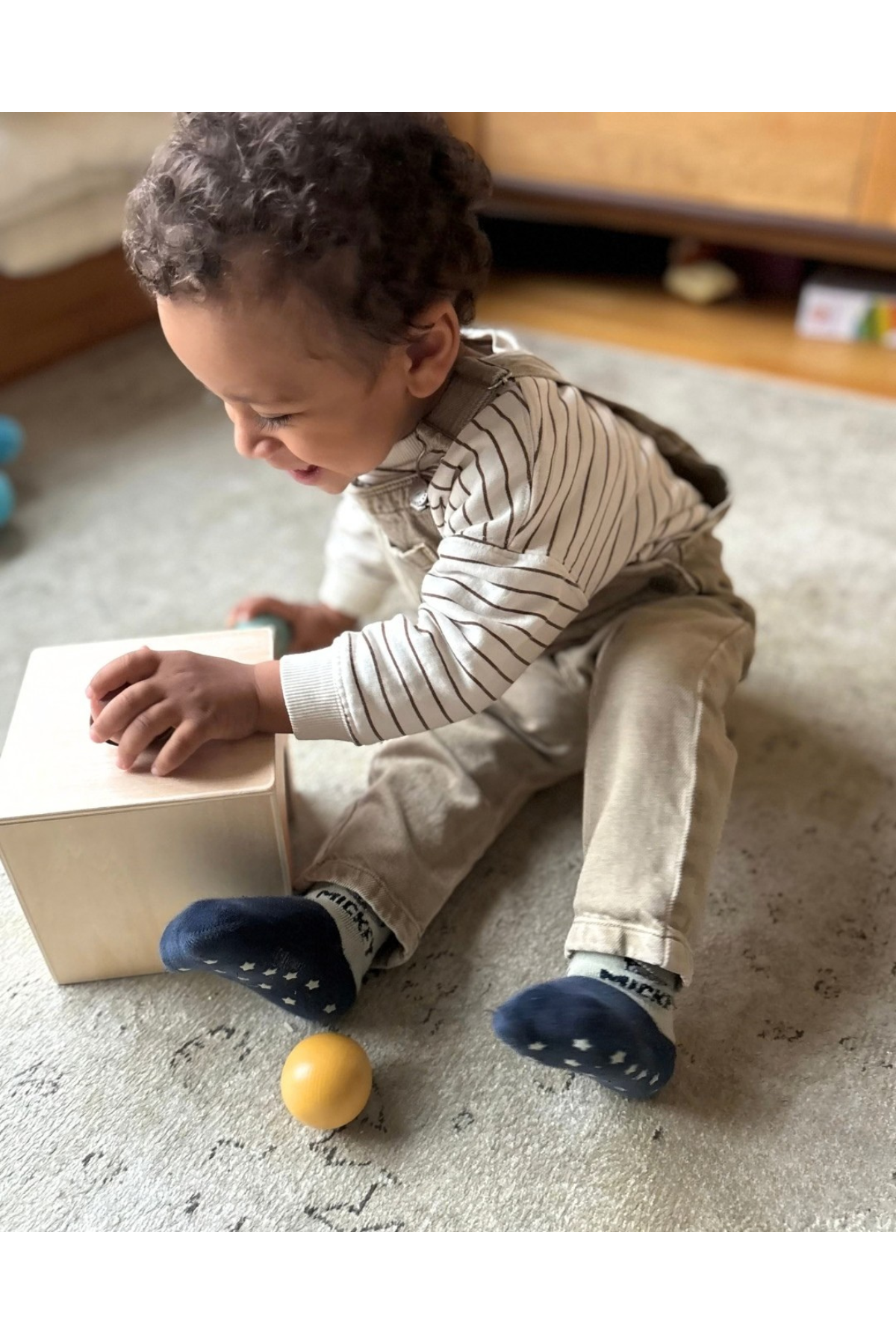 Barn að leika með Montessori object permanence box með þremur trékúlum.