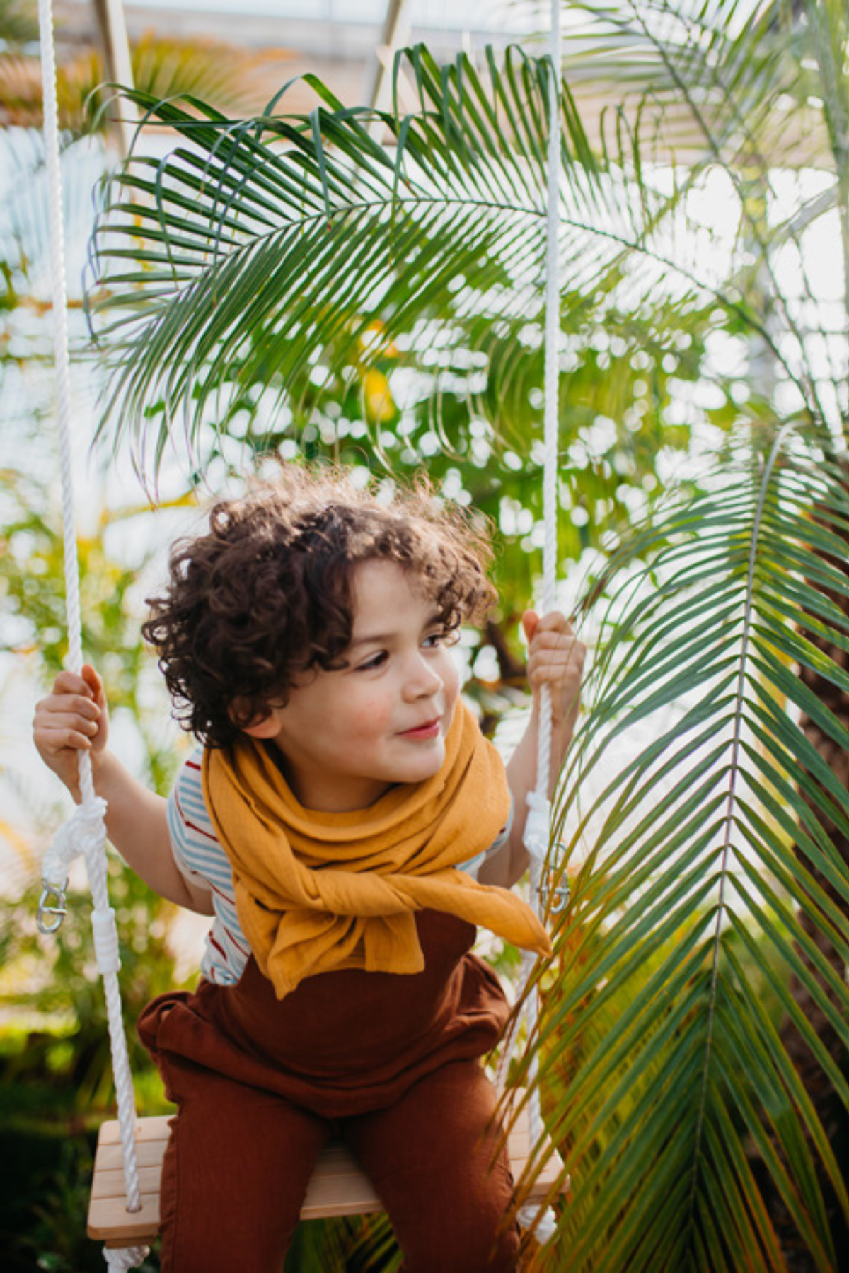 Barn að leika sér í 3in1 rólusetti meðal plantna