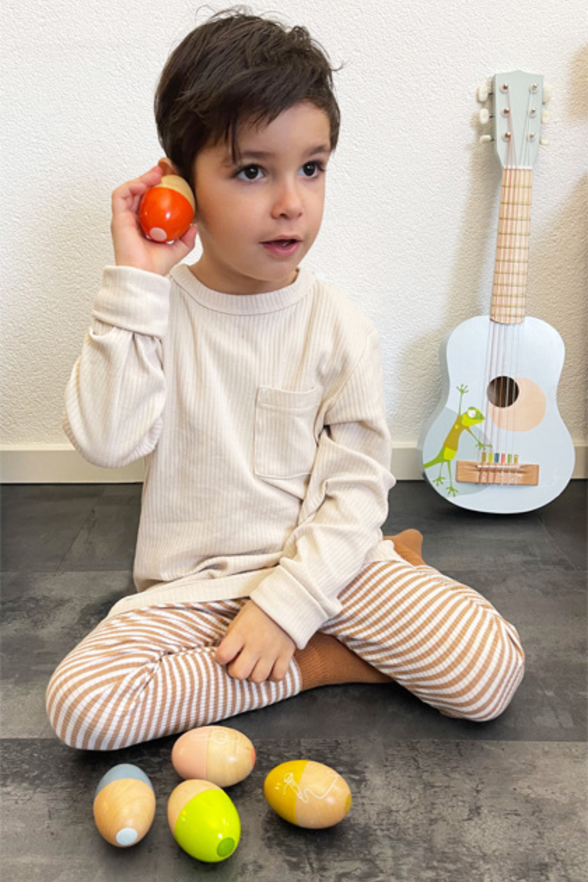 Barn að hlusta á egg hristara úr við – tónlistarleikfang fyrir börn