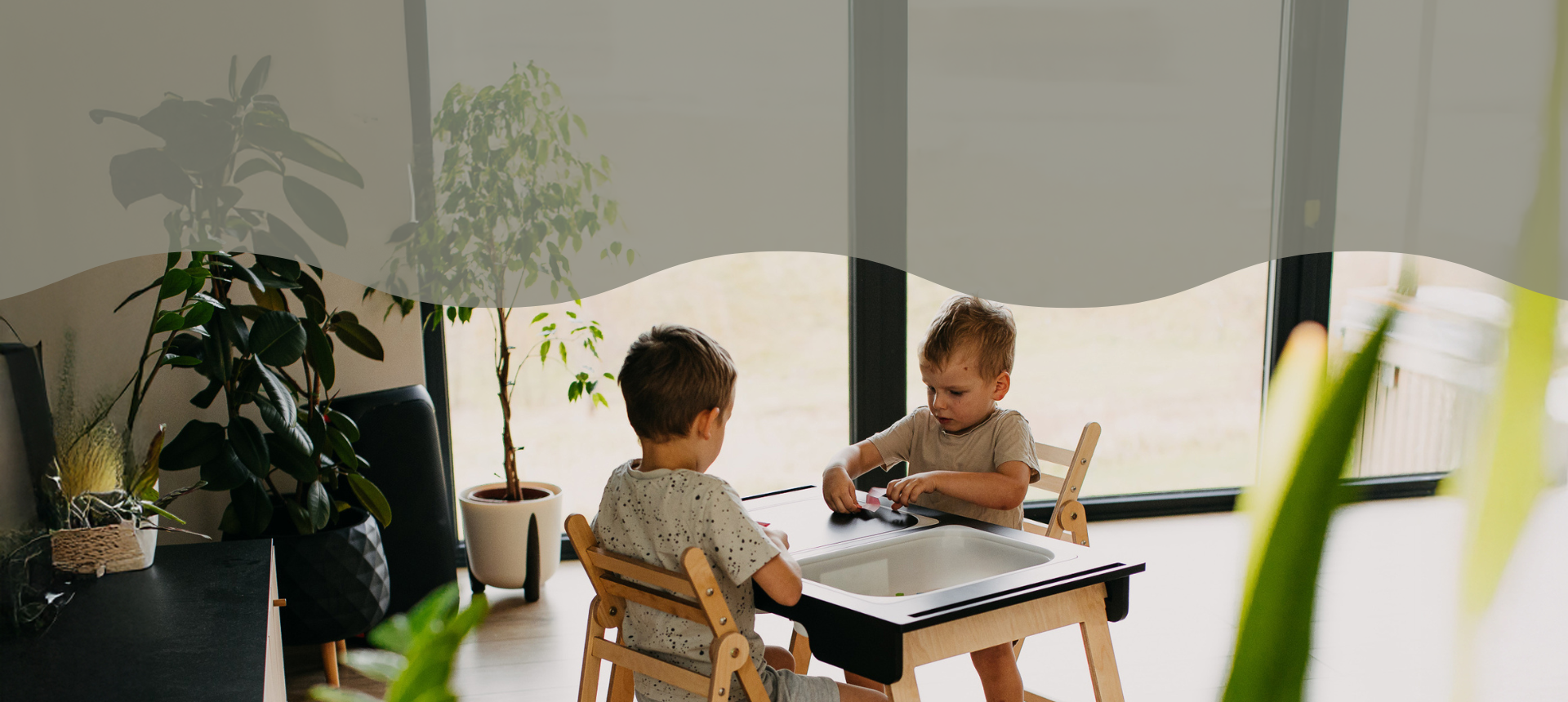 Tvö börn sitja við Skynjunarborðið sem fæst hjá White Noise Barnavöruverslun.
