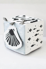 Cube-shaped toy with whale design on a light gray background