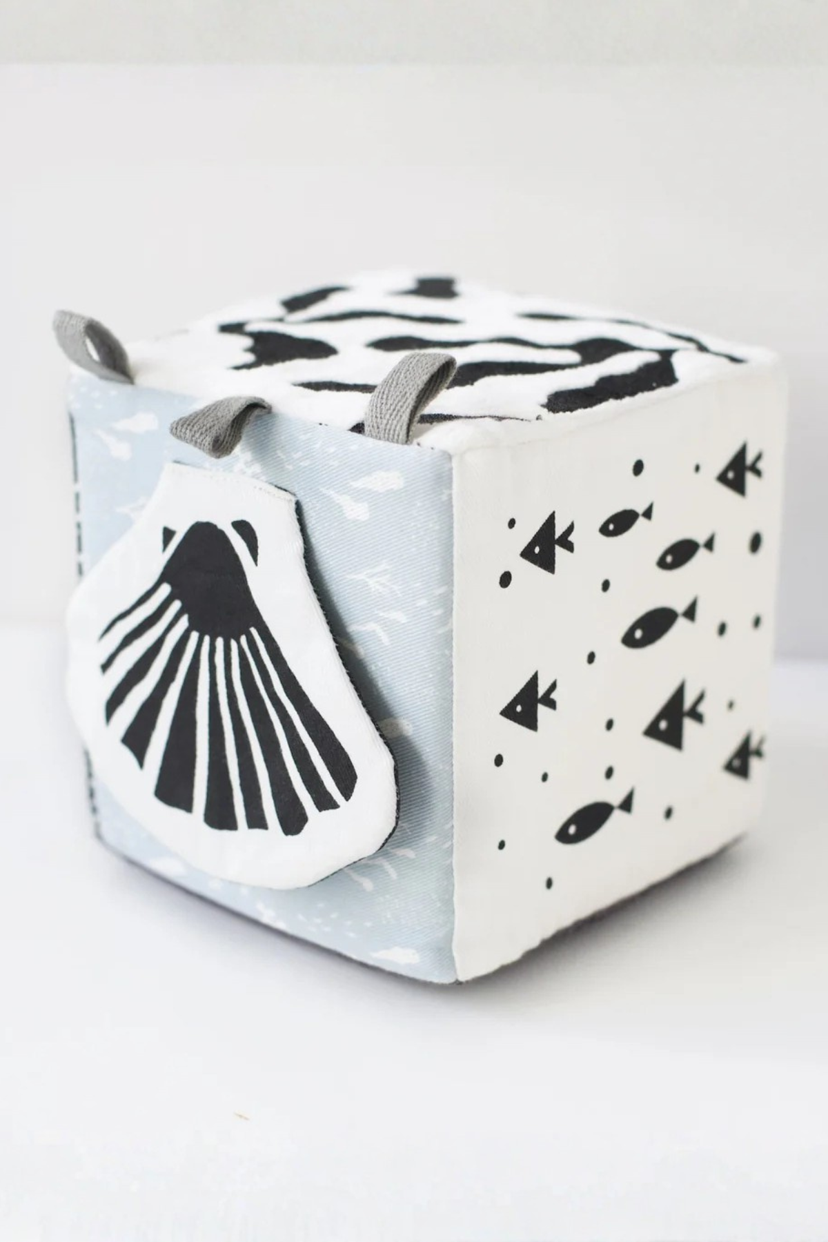 Cube-shaped toy with whale design on a light gray background