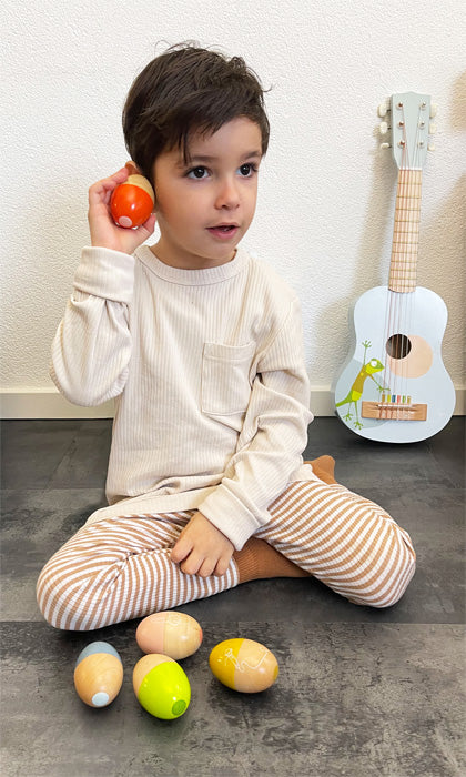 Barn að hlusta á egg hristara úr við – tónlistarleikfang fyrir börn