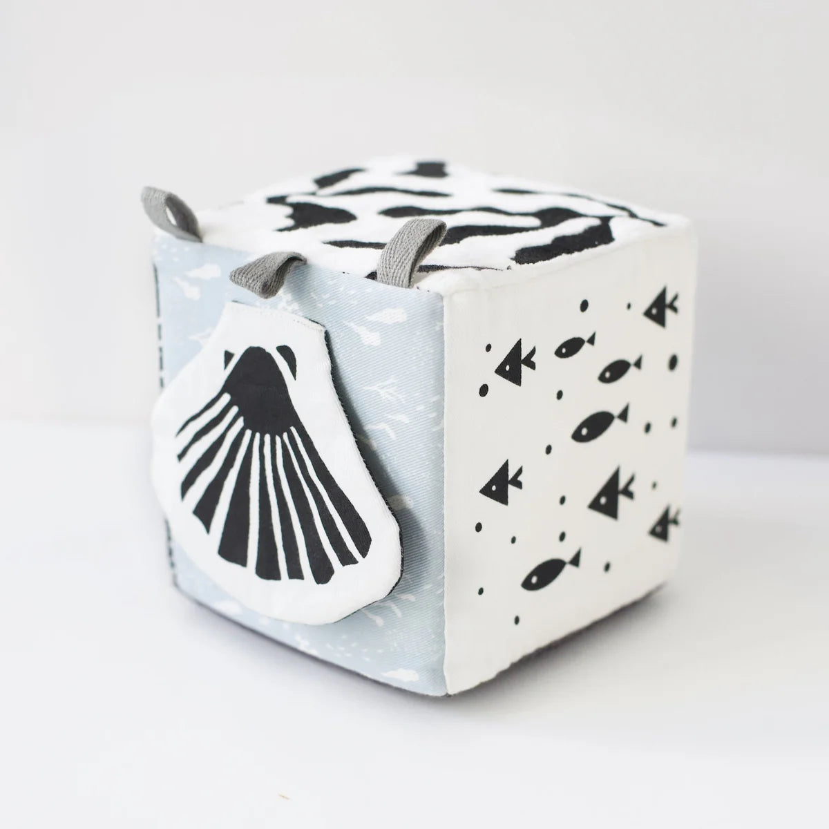 Cube-shaped toy with whale design on a light gray background