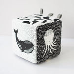 Cube-shaped toy with black and white whale and octopus designs on a white background