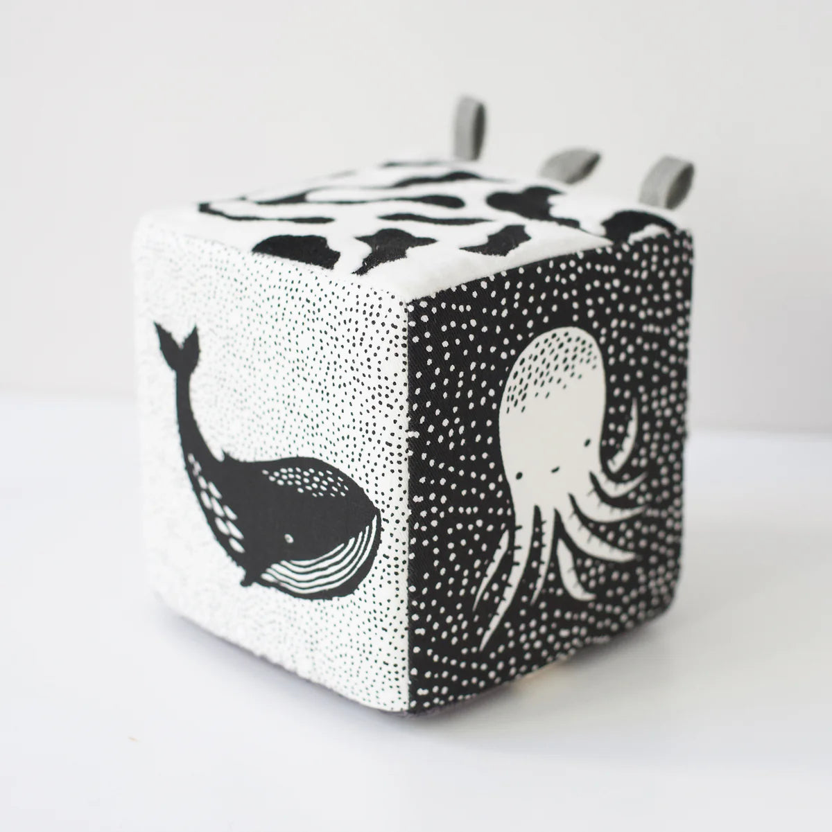 Cube-shaped toy with black and white whale and octopus designs on a white background