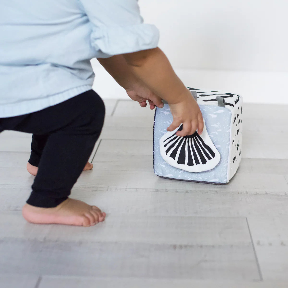 Child playing with a toy box on a light wooden floor
