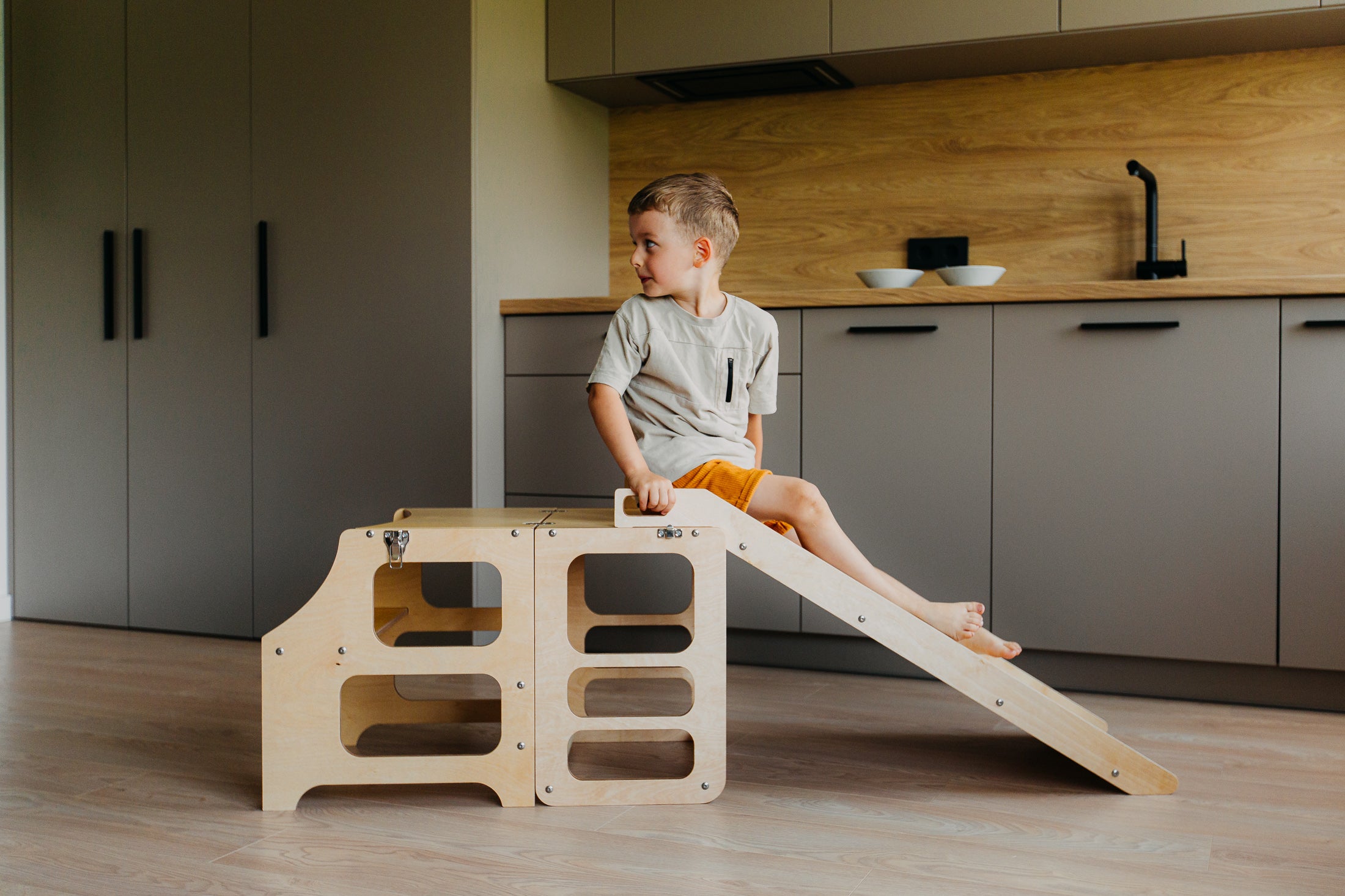 Barn að leika sér á hvítum Step and Slide hjálparturni með rennibraut í eldhúsi